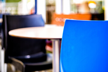 Empty table outside restaurant cafe with two colorful blue chairs on sidewalk street and bokeh background with nobody