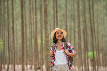 people and lifestyles adventure, travel, tourism, hike and people concept - traveller women walking in the forest of smiling  walking with backpack, hat in woods.