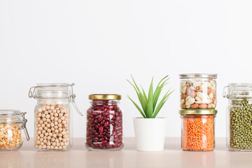 Vegan protein source. Beans, peas, chickpeas, lentils, mung, peanut in glass jars on white and beige background. Healthy vegetarian food. copy space