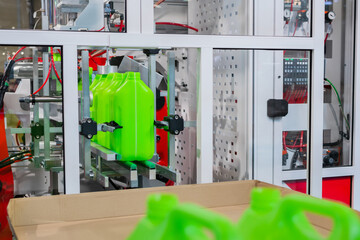 Empty green plastic jerrycans moving on conveyor belt of automatic pet blow molding machine at...
