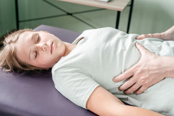 Osteopath practitioner releasing the diaphragm of a female patient, rib cage release massage,...