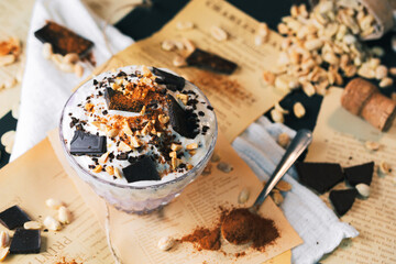 Obraz na płótnie Canvas Dessert. Yoghurt dessert with chocolate and peanuts. Vintage dessert with cinnamon. Dessert served on a newspaper.