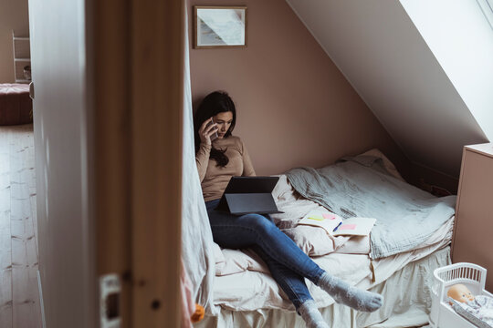 Kvinna pratar i mobiltelefon i sovrum hemma