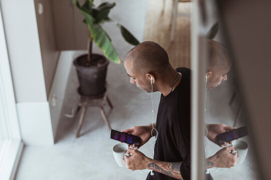 Man med h&ouml;rlurar anv&auml;nder smartphone hemma