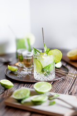 Bright photography of a cold drink, a glass of mojito with mint leaf, ice, lemon and sugar on a...