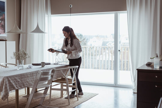 Kvinna st&auml;ller ner dator och mobiltelefon p&aring; matbord