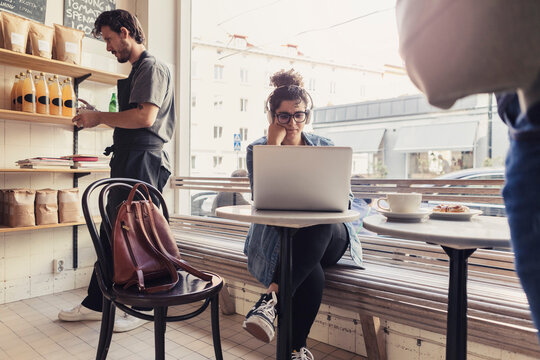 Fokuserad gäst använder laptop på café