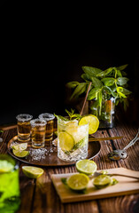 Dark photography of a cold drink, a glass of mojito with mint leaf, ice, lemon and sugar with...