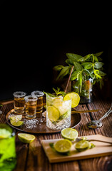 Dark photography of a cold drink, a glass of mojito with mint leaf, ice, lemon and sugar with...