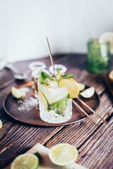 Bright photography of a cold drink, a glass of mojito with mint leaf, ice, lemon and sugar on a wooden table with retro style