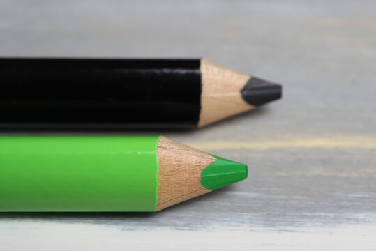 Closeup of isolated colorful black and green crayons on wood background - kiwi coalition concept