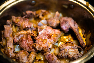 Cooked lamb meat shoulder chops chucks cut in frying pan and onions to make traditional Kazakh or Uzbek pilaf or plov macro closeup © Andriy Blokhin