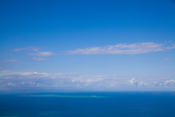 Naklejka na ściany i meble Poster of the blue sky over blue ocean. Blue wallpaper. Ocean view from the top of Cook Island in Australia on the Great Barrier Reef. Turquoise water with white shallows. Sunny tropical day. 