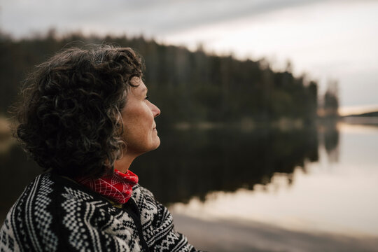 Kvinnlig utforskare tittar ut &ouml;ver sj&ouml; i skog