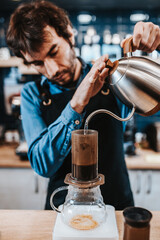 Barista pours boiling water from a kettle into a filter - a drip method for brewing coffee