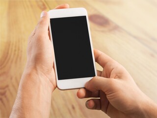 Male hands using smart phone with a blank screen monitor for graphic display montage.