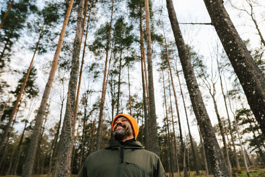 Leende man st&aring;r bland tr&auml;d i skog