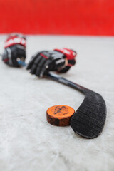 Hockey puck, gloves and hockey stick on ice - close-up selective focus