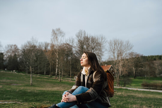 Fridfull kvinna sitter med slutna &ouml;gon p&aring; &auml;ng