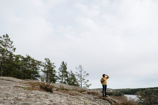 Vandrare st&aring;r p&aring; berg i skog och tittar bort
