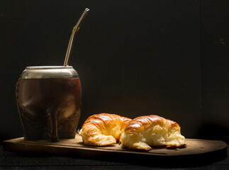 Closeup shot of Argentinian yerba mate tea with medialunas/croissants on a wooden table