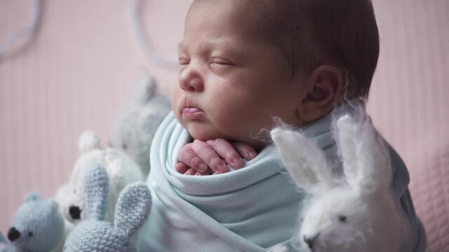 Preparing a newborn girl for a photo session. Little girl smiles among the toys. Shooting backstage of newborns photography.