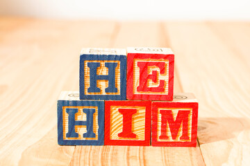 Spectacular wooden cubes with the word HE HIM on a wooden surface.