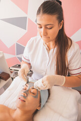 Young female having the clay mask wiped off her face by a qualified specialist