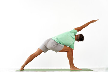 back view of sporty man practicing yoga in yoga class, making stretching back. Healthy lifestyle,...