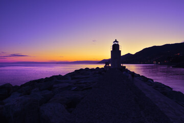 Fototapeta na wymiar view of the lighthouse in Camogli with amazing sunset over the sea