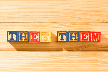 Spectacular wooden cubes with the word THEY THEM on a wooden surface.