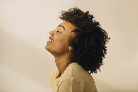 Skrattande kvinna med st&auml;ngda &ouml;gon framf&ouml;r vit bakgrund