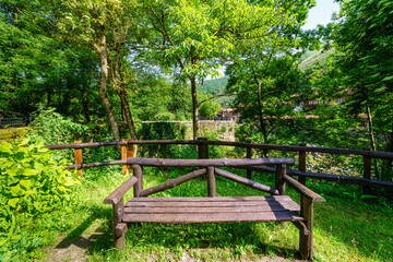 Fototapeta na wymiar Wooden bench in a park next to a mountain stream.