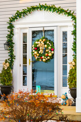 Fototapeta na wymiar Christmas decoration wreath on door on single family residential suburbs house in northern Virginia with glass windows and golden balls