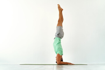 Young man acrobatics gymnastic doing a handstand studio isolated on white background, athletic...