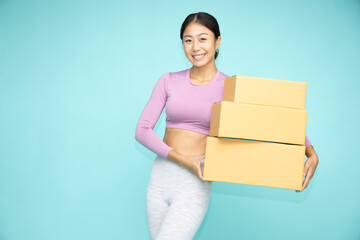 Happy Asian sporty woman  holding package parcel box isolated on green background, Delivery and shopping express concept