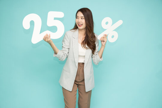 Asian business woman showing and holding 25% number or twenty five percent isolated over light green background