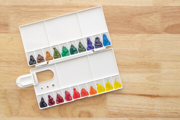 Watercolor paints set. Color in watercolor palette dirty on wooden background.