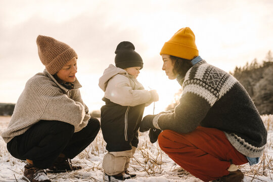 Mammor umg&aring;s med dotter i sn&ouml;n under solnedg&aring;ng