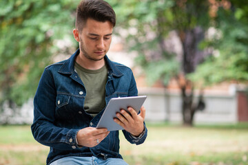 Man using his tablet while sitting on a banch in the park