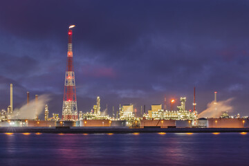Fototapeta na wymiar Night scene with illuminated petrochemical production plant on riverbank, Port of Antwerp