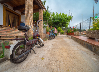 Motocicleta vintage aparcada en una calle de pueblo con flores 