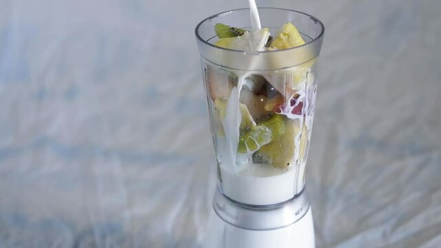 Versare del latte per preparare un frullato di frutta
