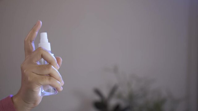 Woman using alcohol spray for sanitization in the room.