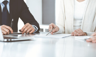 Fototapeta premium Business people discussing contract working together at meeting in modern office. Unknown businessman and woman with colleagues or lawyers at negotiation