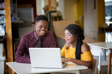 Couple Black skin businesspeople using laptop computer in cafe.