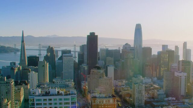 San Francisco Financial District aerial view. Famous skyscrapers at dusk. Bay bridge in the background. California, United States. Shot in 8K.