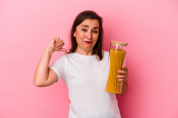 Middle age caucasian woman holding a pasta jar isolated on pink background feels proud and self confident, example to follow.