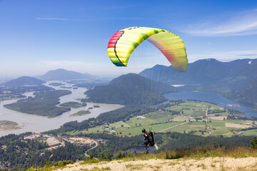 Adventurous Woman Running to Take Off the Mountain Top with a Paraglider to Fly. Harrison Mills near Chilliwack, British Columbia, Canada.
