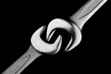 Two steel wrenches isolated on black background closeup. Concept of love, relationship, valentines...